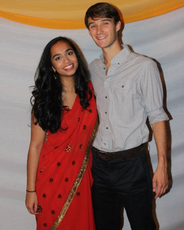 Sneha on the left wears a red sari and poses next to her husband, Michael.