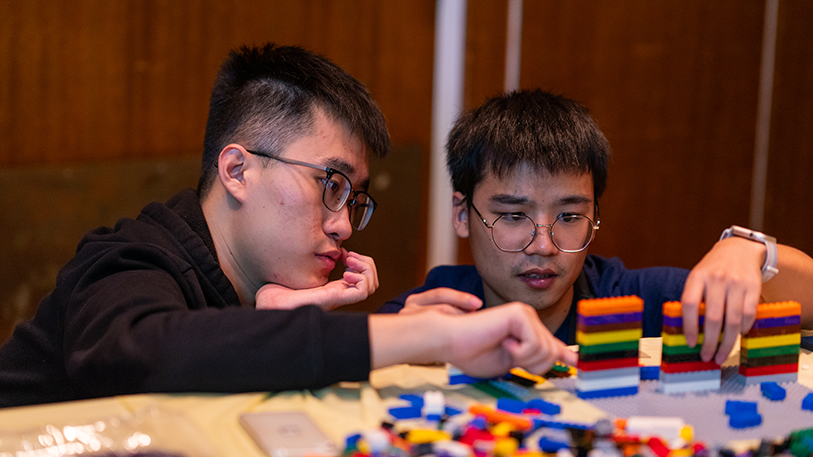 Two male students thinking about how to build their lego structure in front of them.