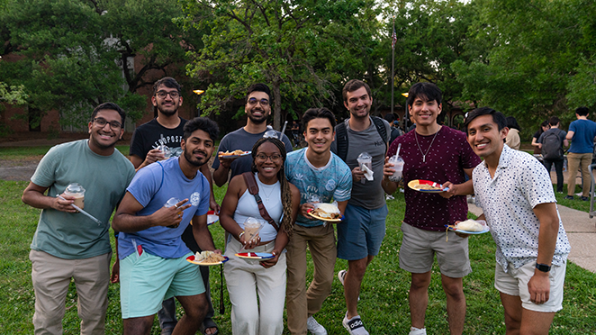 Group of students holding plates of food and boba.
