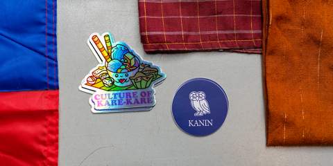 Two stickers on a table with three different fabric. The first sticker says "Culture of Kare-Kare" and the other sticker has the Rice logo and the word "Kanin" under it.