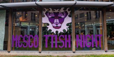 Painted artwork in purple and white and the words McScottish Night in purple and all caps span across three large window panels.