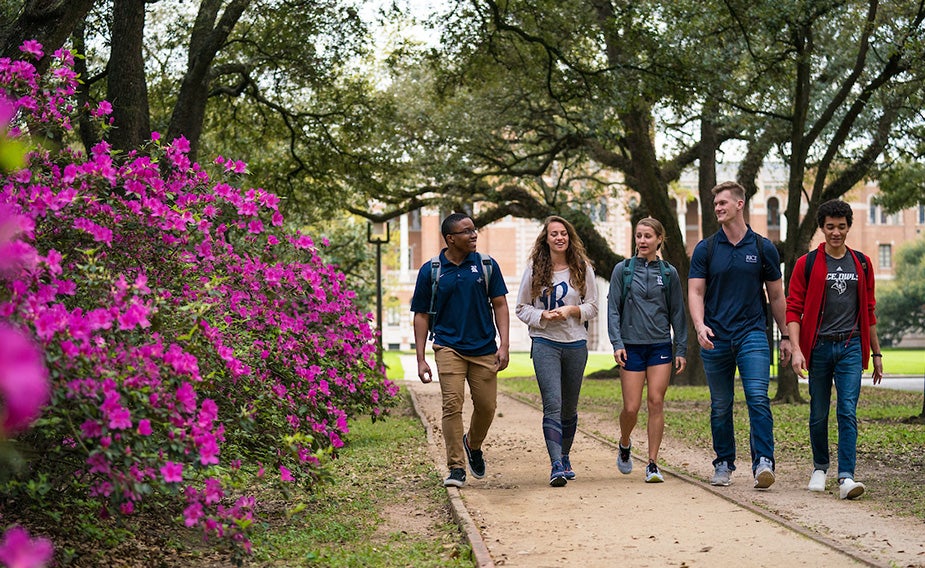 Five Rice students walking on campus pathway