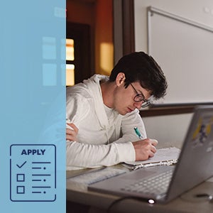 A male student studying by a laptop