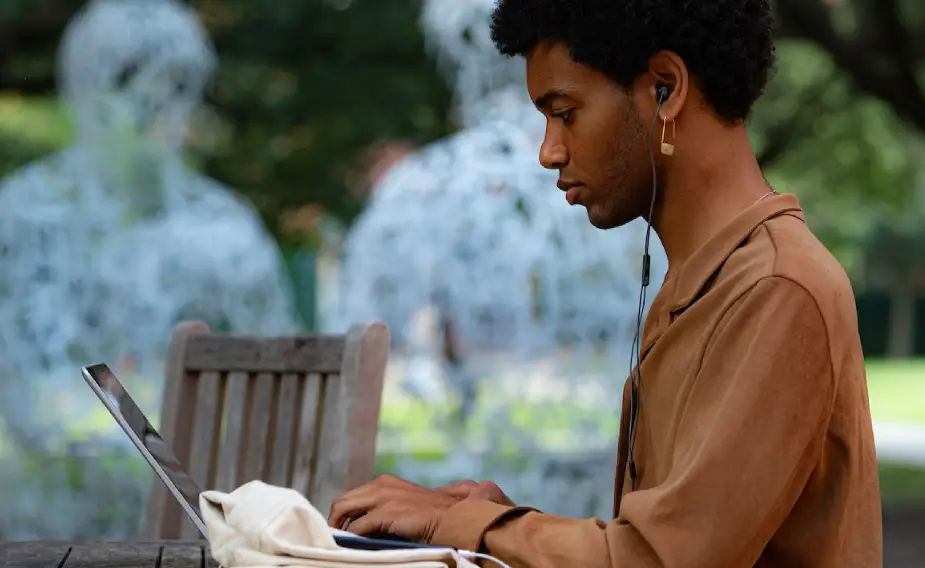 Student sitting outside typing on laptop