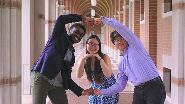 Sarah poses for a picture with her fellow co-coordinators. She's in the center while the two boys use their arms to make a circle around her face.