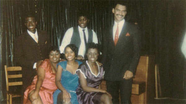 A group of students dressed up for an event in suits and dresses pose for a picture.