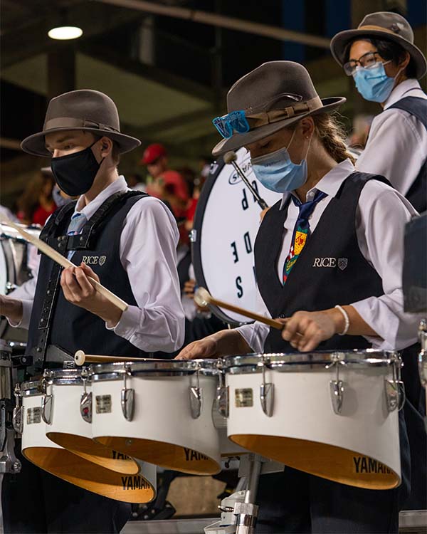 Two students in uniform play the drums as part of the Rice MOB (Marching Owl Band).