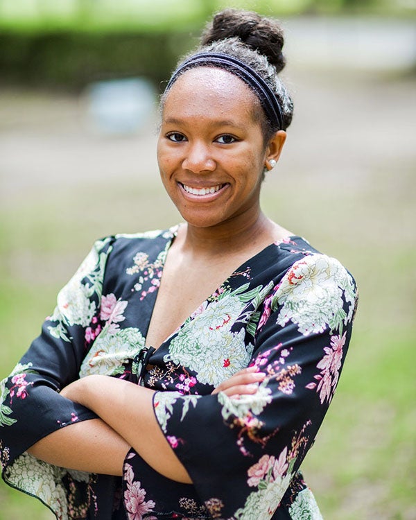 Valencia poses for a headshot, with a confident smile and her arms crossed in front of her.