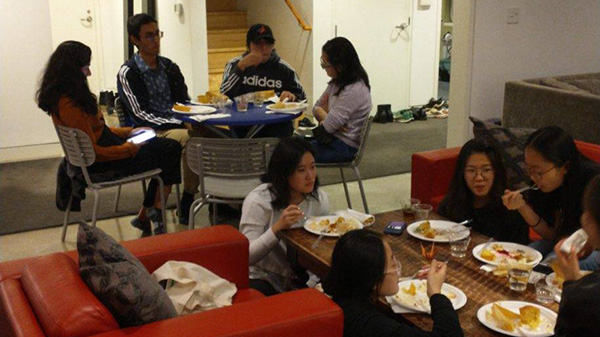 A wide shot of students eating and socializing on various couches and sitting at various tables.