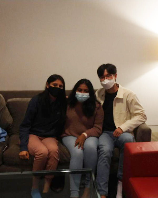 Three Rice students wearing masks sit on a couch and pose for a picture.
