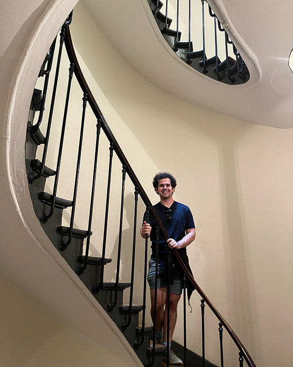 A picture of Zach standing on the steps of a winding staircase.