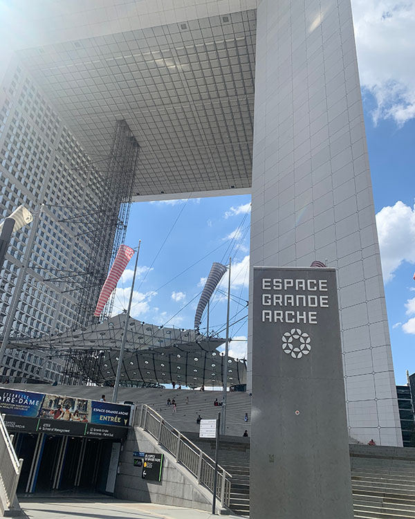 Photo shows a sign that says "Espace Grande Arche" in front of a large archway.