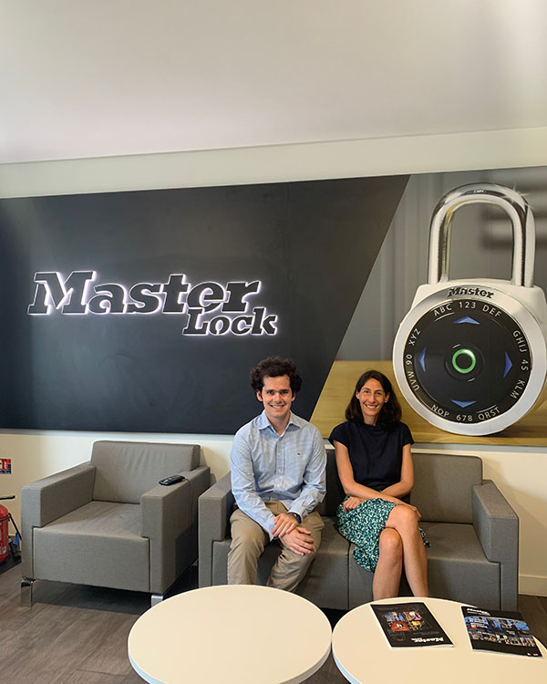 A picture of Zach and Leslie seated next to each other in front of a sign that says Master Lock.