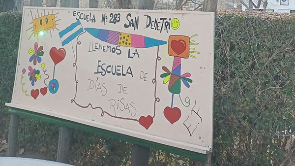 A whiteboard in front of a school in San Demetri has the name of the school written on it in Spanish as well as colorful child-like drawings.