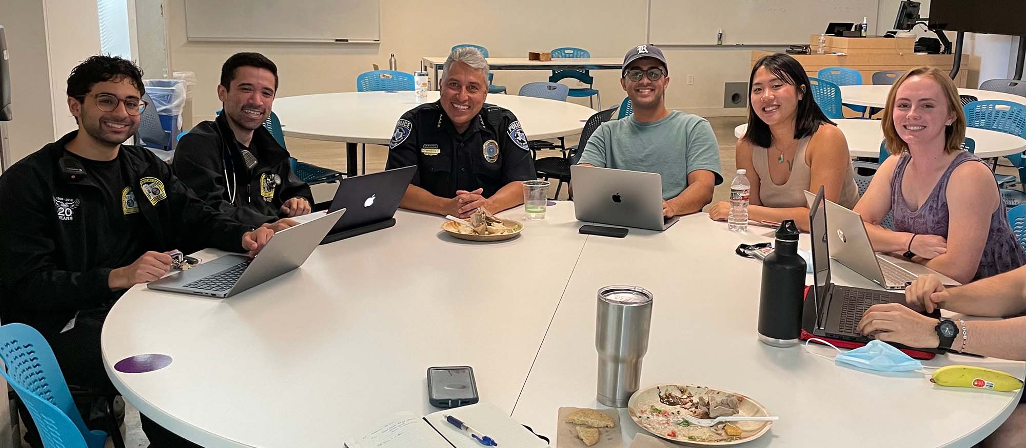 A group photo of two Rice students who are part of REMS and emergency services smiling at a table.