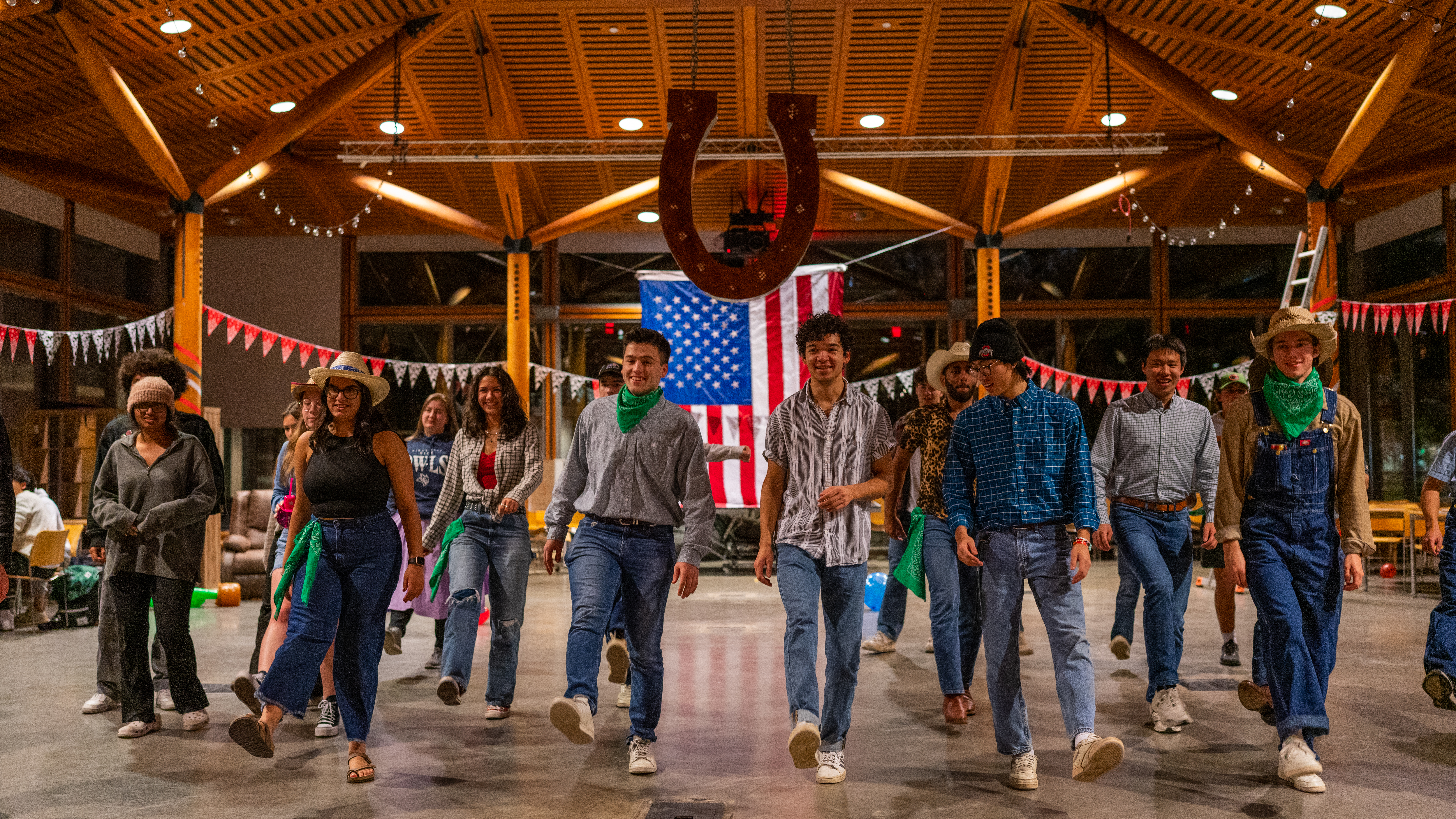 A group of students wearing country-style outfits, performing a line dance and kicking one foot up.