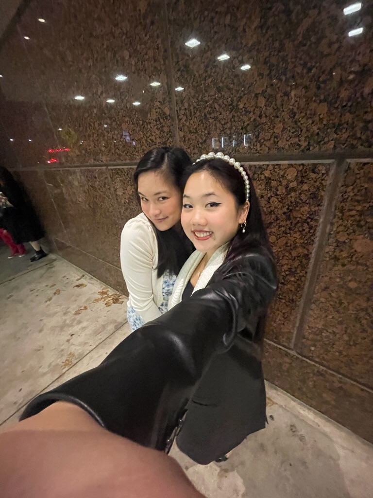 Selfie taken in 0.5 camera mode of two girls smiling at the camera.
