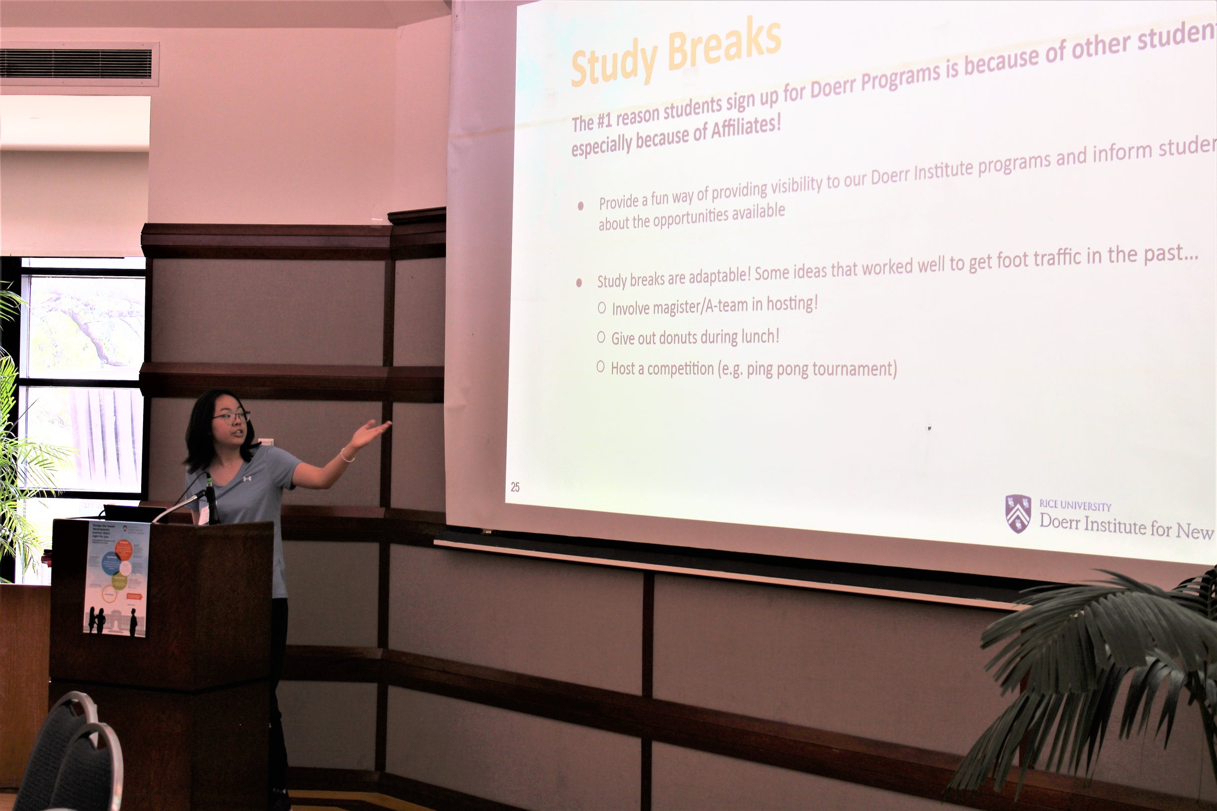 Female student is pointing to a projected screen to the left of her.