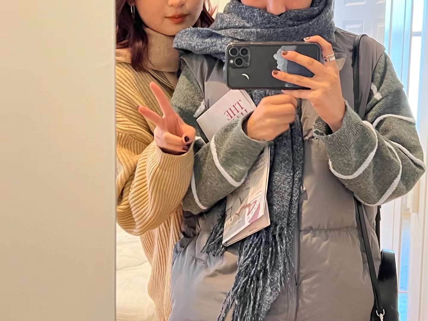 A mirror selfie of two females wearing winter clothes.