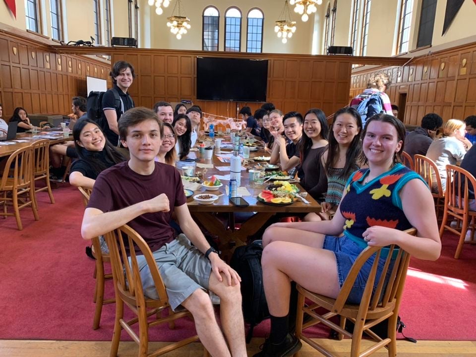 Group of students sitting at a table with food in front of them.