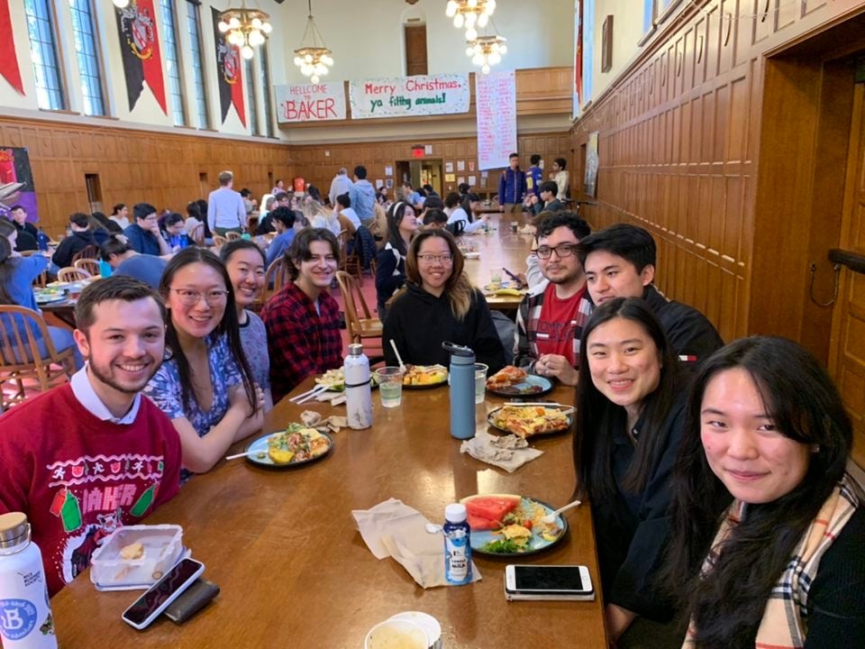 Group of students sitting at a table with food in front of them.