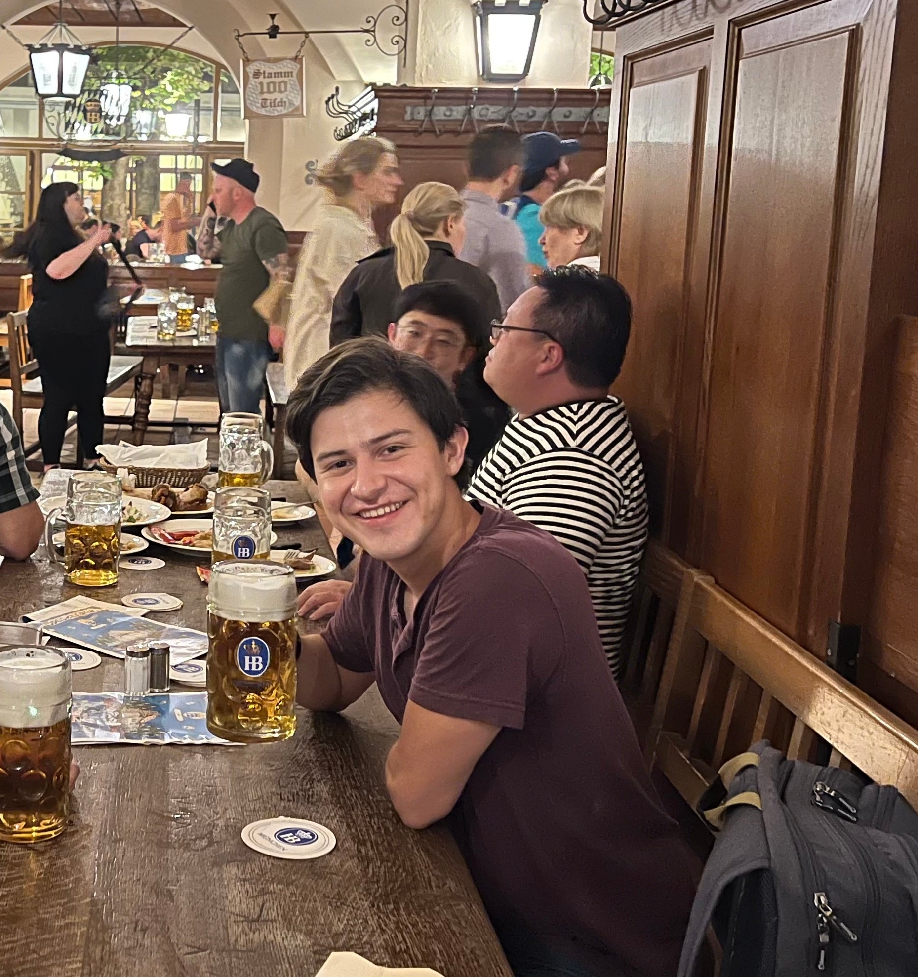 Xavier holding a pint of beer in his hand, sitting at a dinner table.