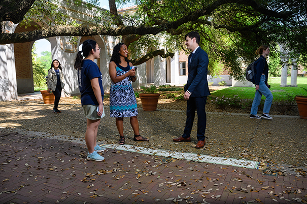Xavier talking to a female professor and female student, standing in a courtyard.