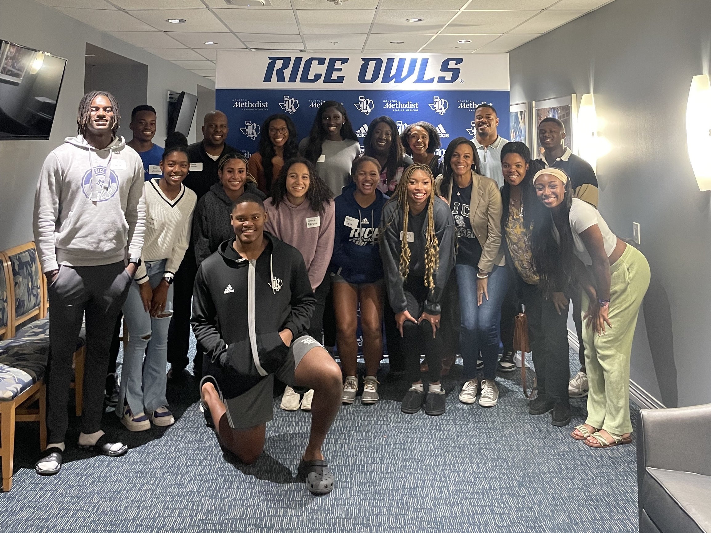 Group of students posing for photo in front of Rice Owls banner