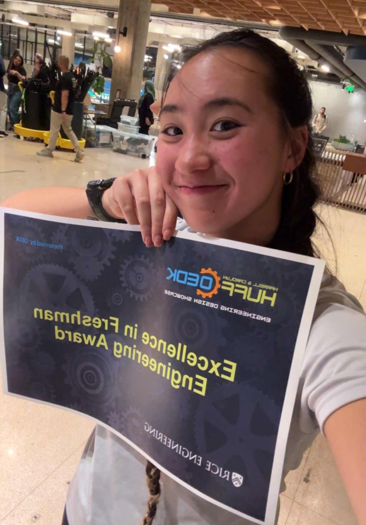 A Rice student taking a selfie and holding a sign saying "Excellence in Freshman Engineering Award"