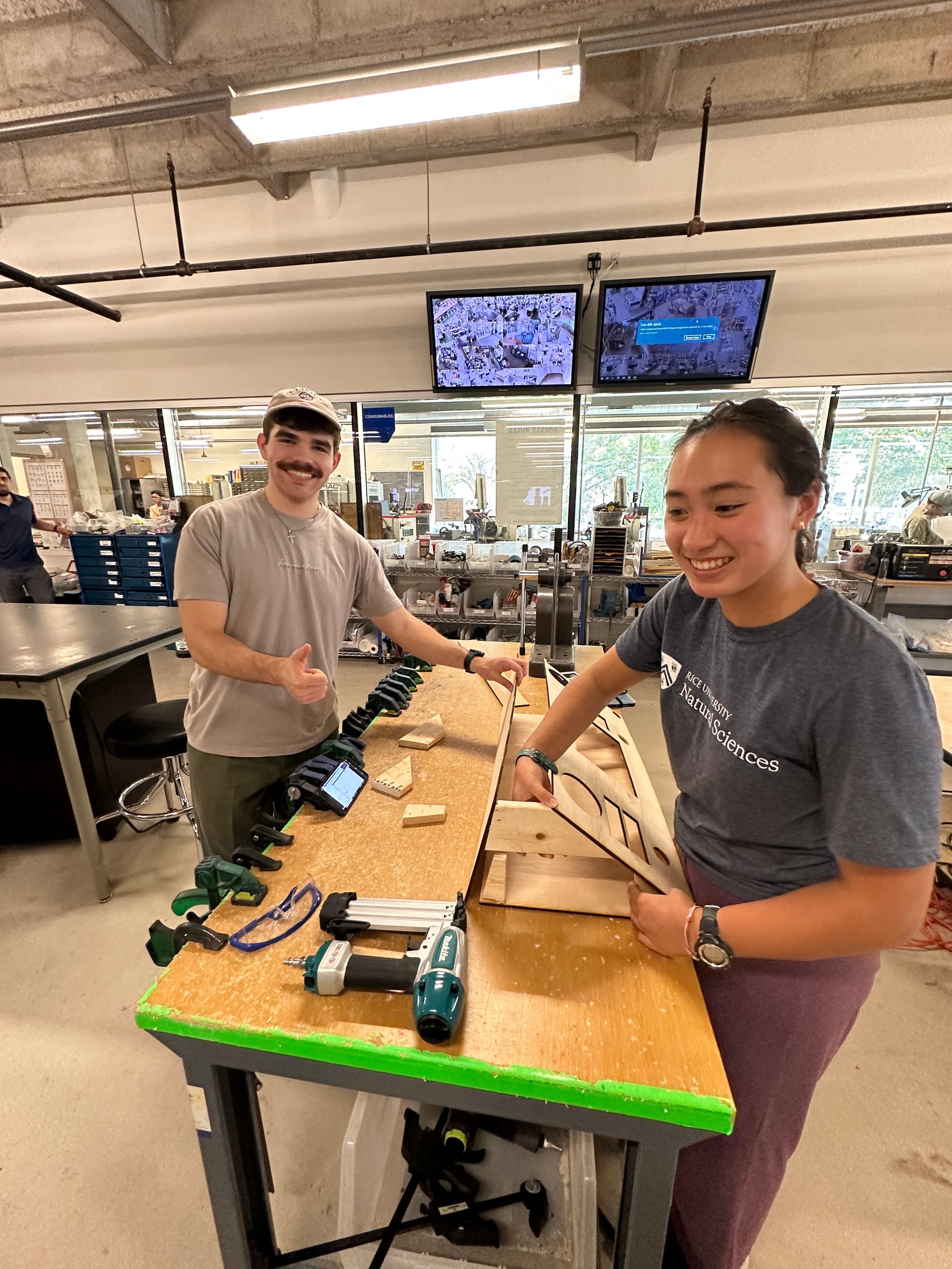 2 college students working on cutting wood at a saw bench 