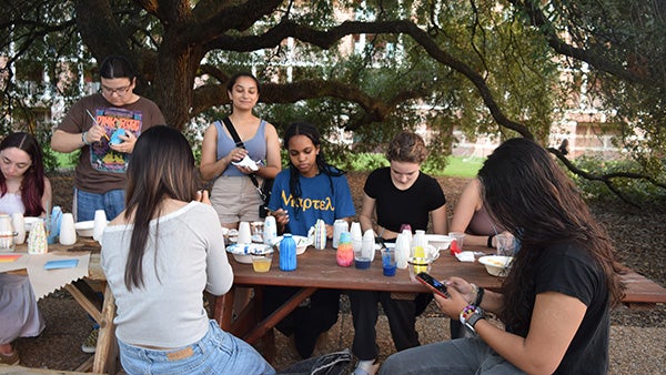 A group of college students painting at a wooden table