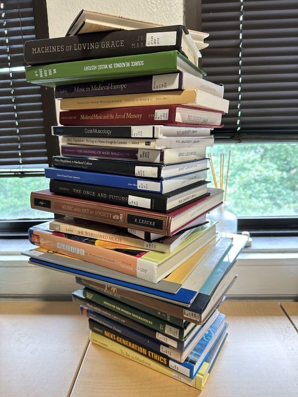 A tall stack of textbooks on a table showing the spines with their titles 