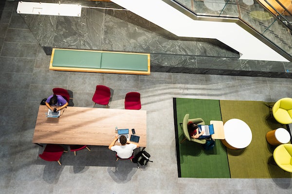 An arial photo of a student working on a laptop at a large wooden table 