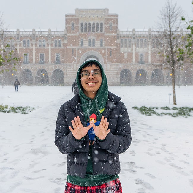 A college student making an own sign with his hands in the snow 