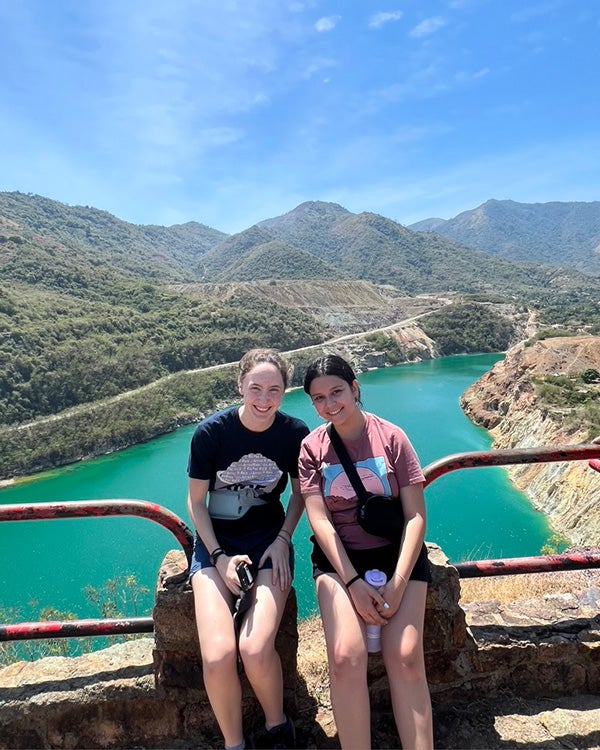 Two girls posing for a photo in front of a bright blue river 