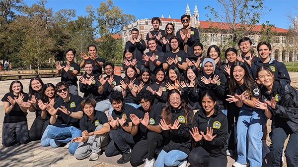 A group of college students posing as a large group all wearing black shirts