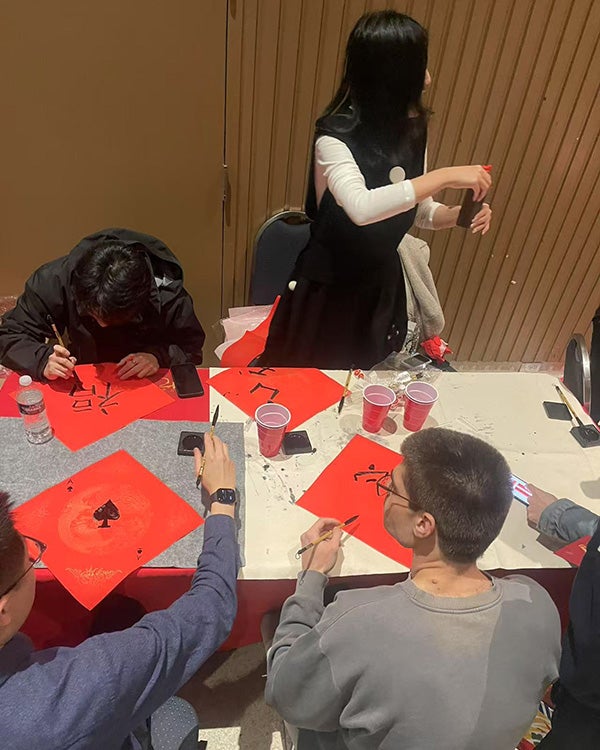 A table of students writing Chinese characters on red paper 