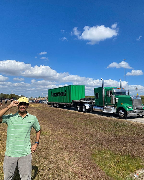 A man posing for a photo in front of a large truck