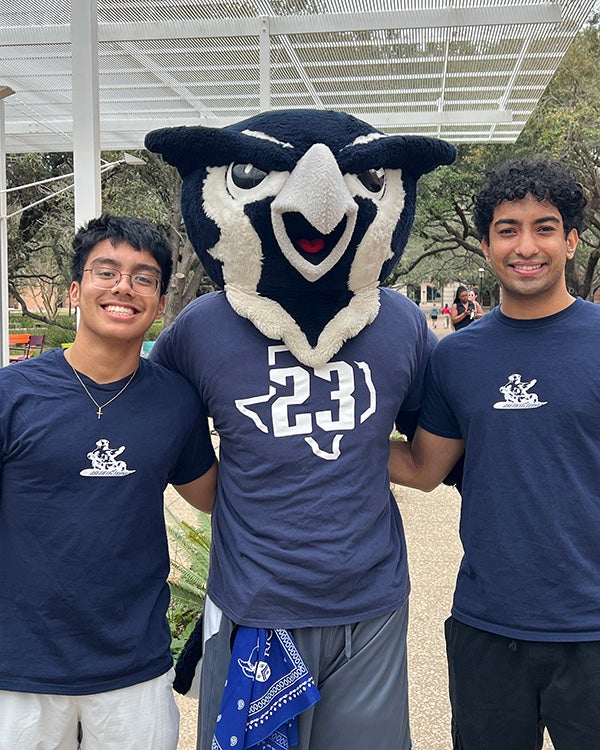 2 college students posing with an owl mascot