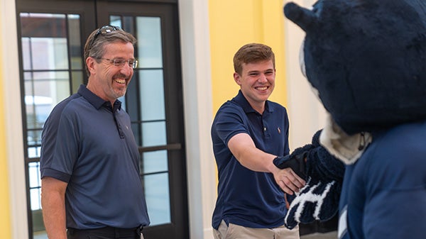 A student shaking Sammy the Owl's hand.