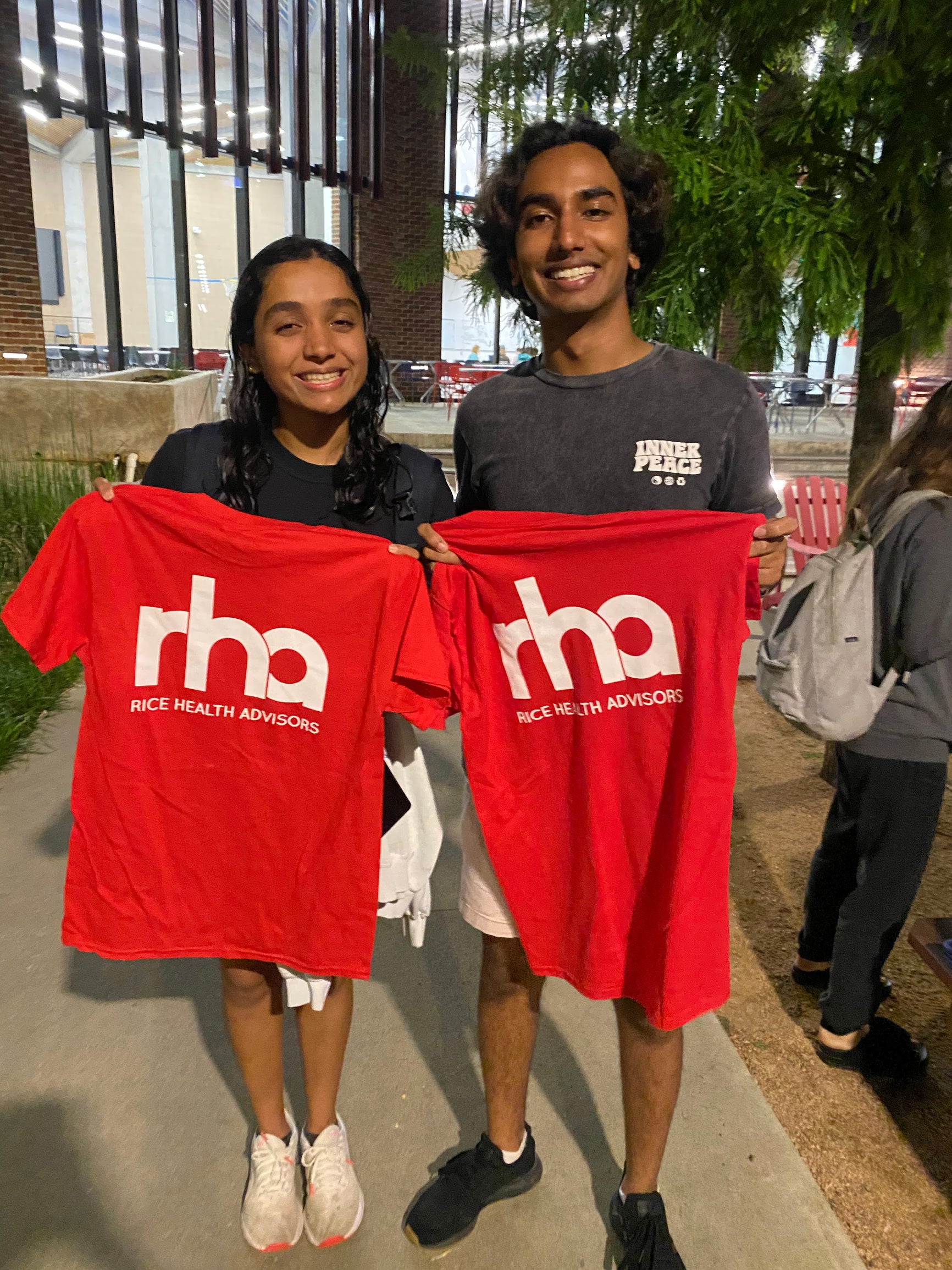 Two students holding up RHA shirts.