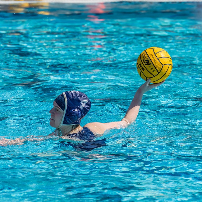 A girl in the pool holding a water polo ball in her hand