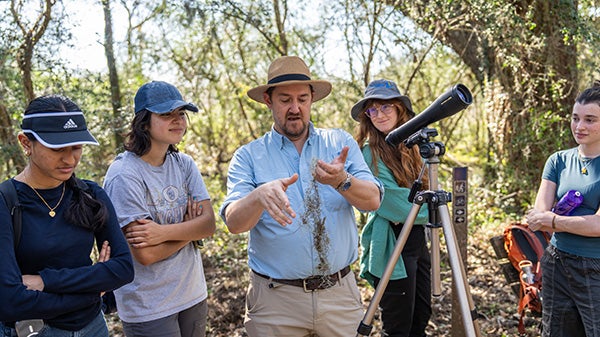 A professor teaches his students about nature at a field trip to Bayou Bend State Park