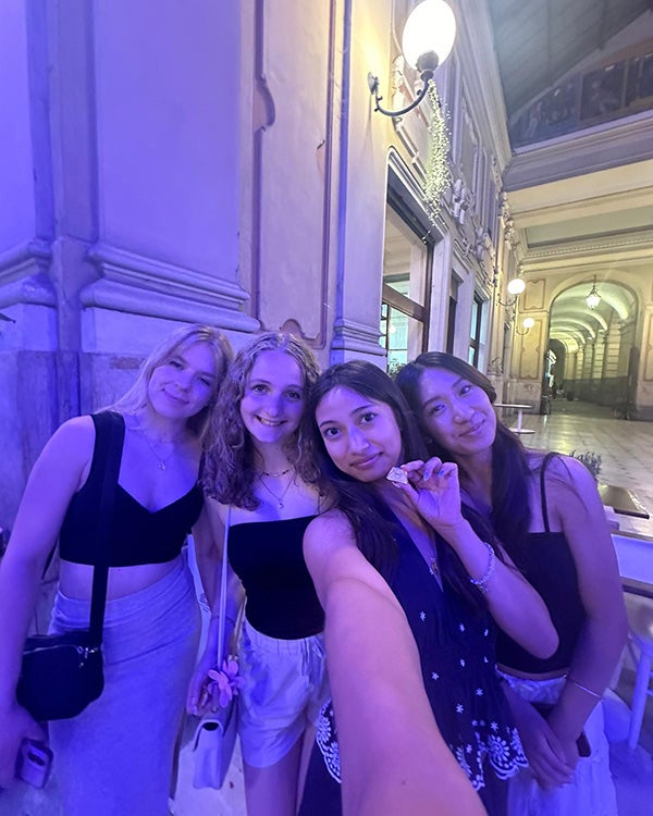 Blog writer Alysa and three study abroad friends take a selfie in a building with classic European architecture