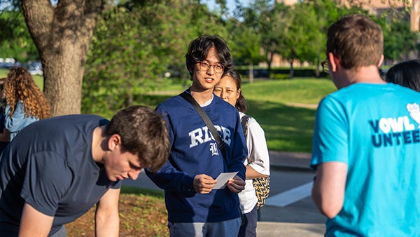 A student in Rice apparel watches someone during a campus tour.