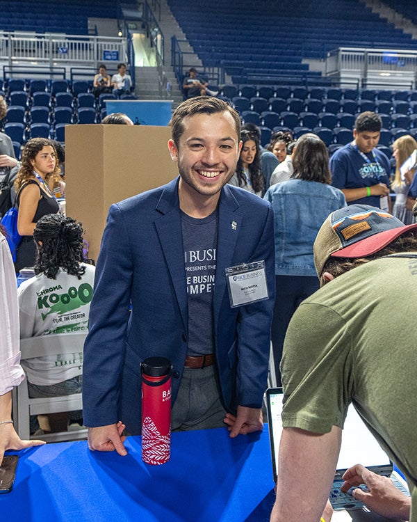 A man from Rice's business school eagerly leans over a table at a career fair.