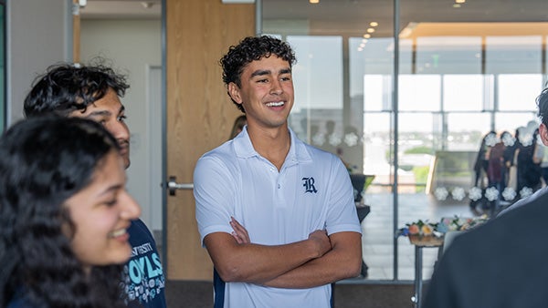 A student with arms crossed happily participates in a campus tour.