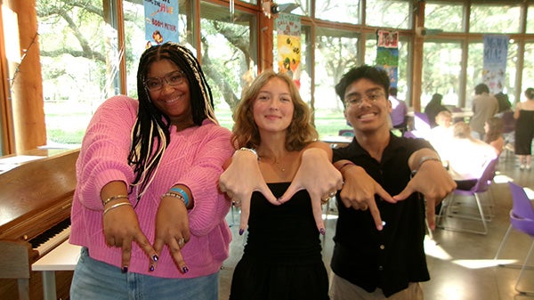 Three students holding up "M" hand signs