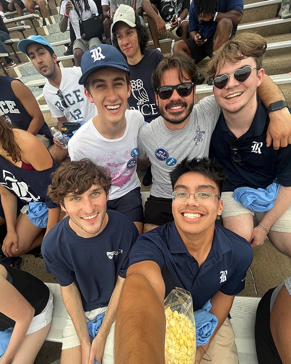 A fisheye photo of male students sitting together on the bleachers