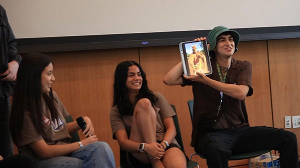 Students sitting in front of a room, one holding up a tablet displaying a kangaroo